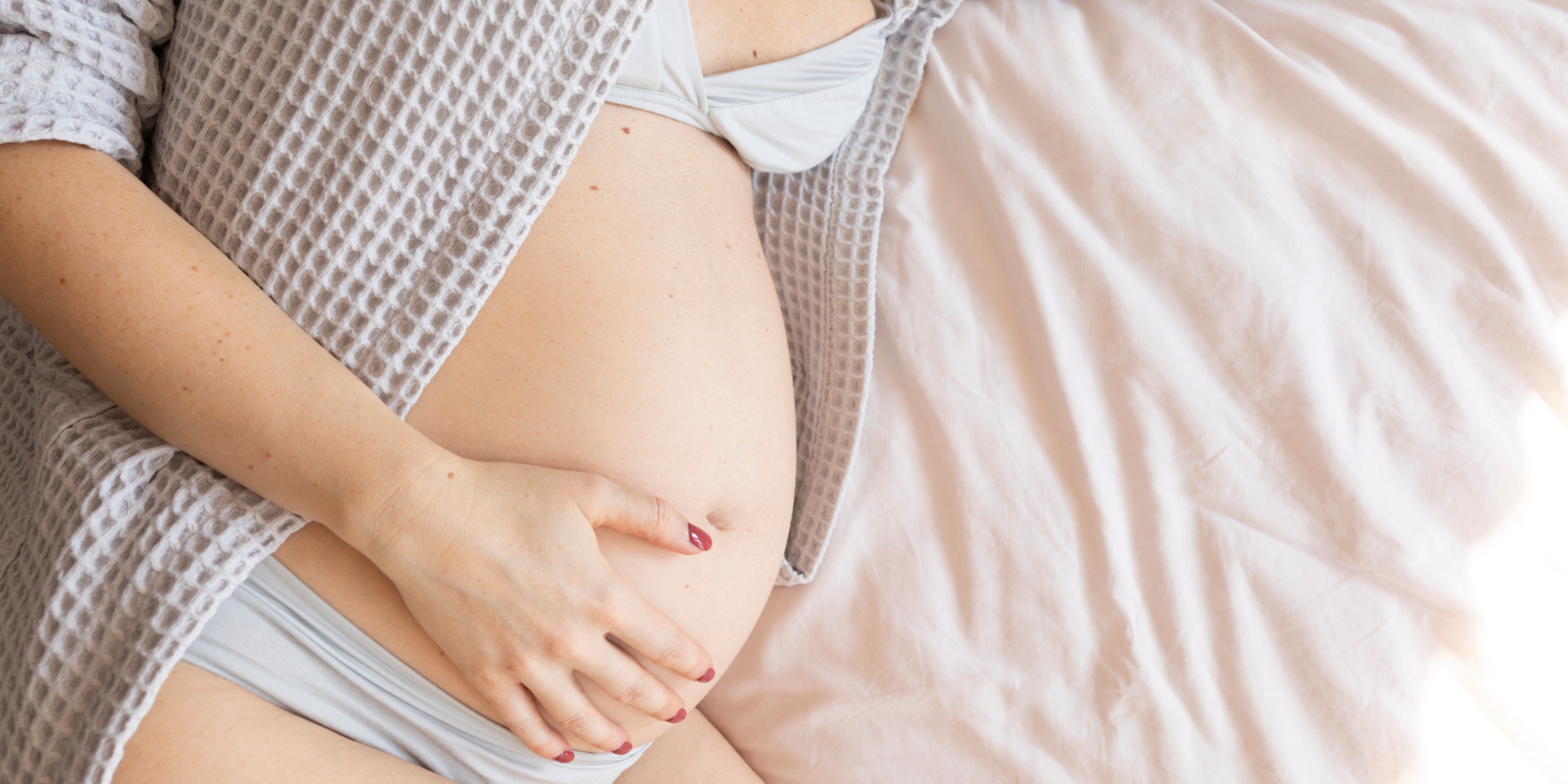 Schwanger werden, Kinderwunsch, schwangere Frau auf Bett